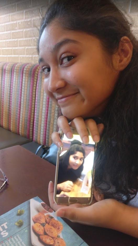 Rashi holding up a phone with a photo of herself on it